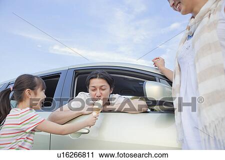 Stock Image - Family Eating Ice Cream at Service Area. Fotosearch
