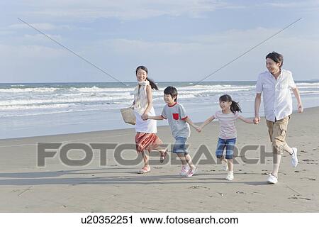 Stock Image - Family Running at Beach. Fotosearch