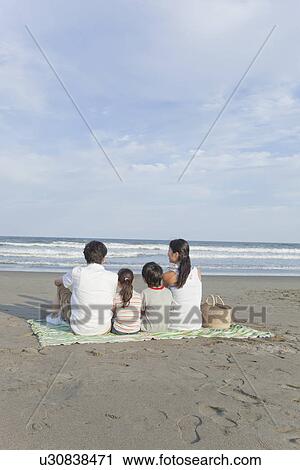 Stock Image - Family Sitting at Beach. Fotosearch