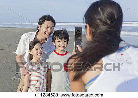 Stock Photo - Family Taking Photo by Cellular Phone at Beach. Fotosearch