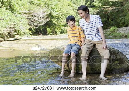 Stock Image - Father and Son Sitting on Rock. Fotosearch