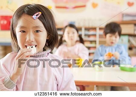 Stock Photograph - Kindergarten Girl Eating Rice Ball. Fotosearch