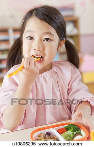 Stock Photograph - Kindergarten Girl Having Lunch. Fotosearch