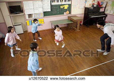 Stock Image - Kindergarten Teacher and Children Playing. Fotosearch