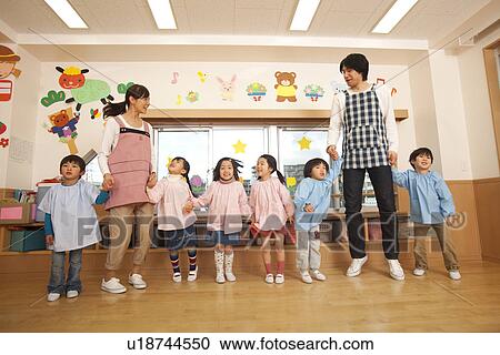 Stock Image - Kindergarten Teacher and Children Playing. Fotosearch