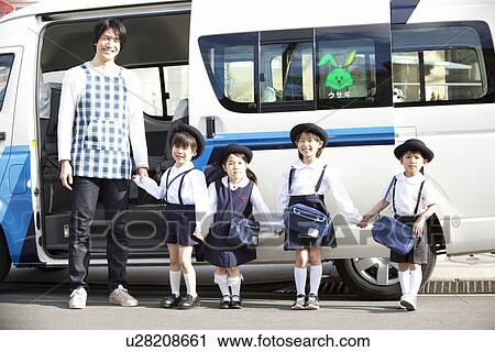 Stock Image - Kindergarten Teacher and Children Standing in front of School Bus. Fotosearch