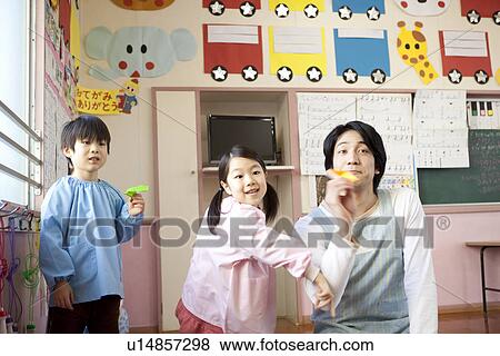 Stock Photo - Kindergarten Teacher and Children Playing Paper Airplane. Fotosearch