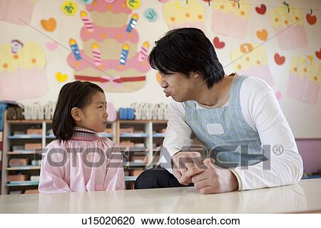 Stock Image - Kindergarten Teacher and Girl Making Face. Fotosearch