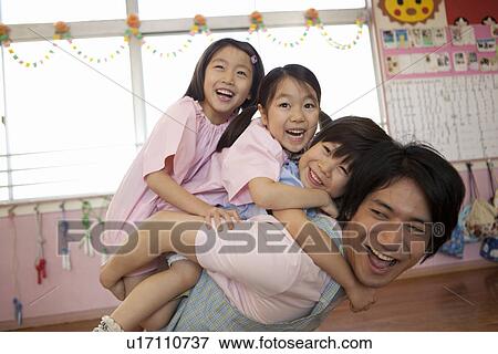 Stock Photo - Kindergarten Teacher Carrying Children on Back. Fotosearch