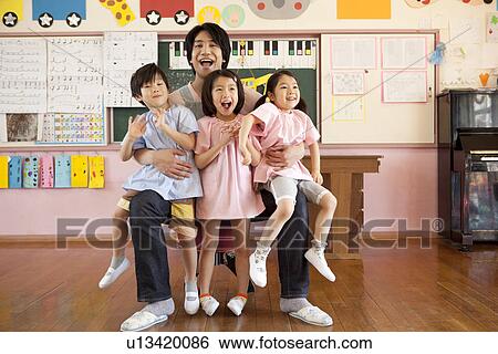 Stock Photograph - Kindergarten Teacher Holding Children. Fotosearch