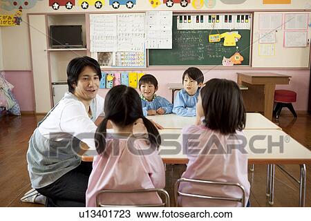 Stock Image - Kindergarten Teacher Talking to Children. Fotosearch