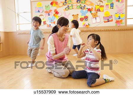 Stock Photo - Nursery Teacher and Children Playing at Day-care Center. Fotosearch