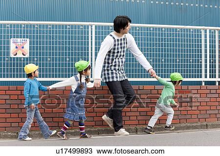 Stock Image - Nursery Teacher and Children Walking. Fotosearch