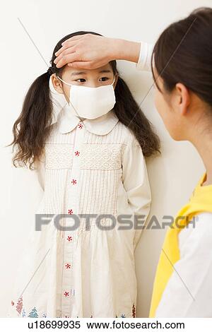 Stock Photography - Nursery Teacher Checking Temperature of Girl. Fotosearch