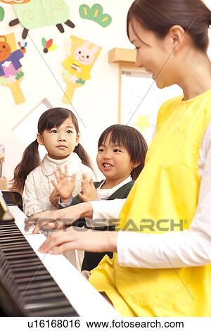 Stock Photograph - Nursery Teacher Playing Piano with Children. Fotosearch