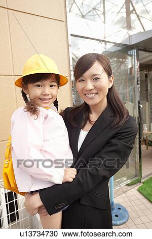 Stock Image - Working Woman Holding Daughter. Fotosearch