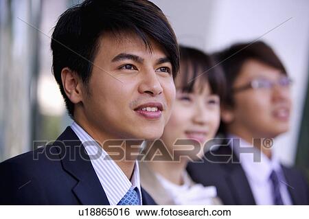 Stock Photograph - Three colleagues looking away together with smile. Fotosearch