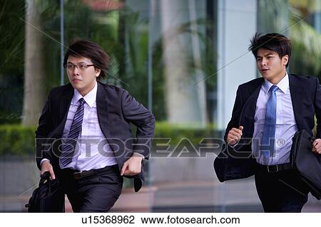 Two businessmen holding briefcase and running together View Large Photo Image Stock Image - Two businessmen holding briefcase and running together. Fotosearch