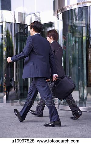 Two businessmen holding briefcase and walking away together View Large Photo Image Stock Photo - Two businessmen holding briefcase and walking away together. Fotosearch