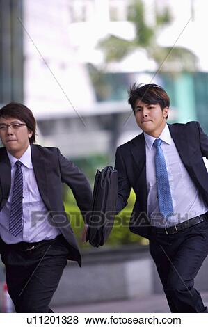 Two businessmen holding briefcase and running together View Large Photo Image Stock Photo - Two businessmen holding briefcase and running together. Fotosearch