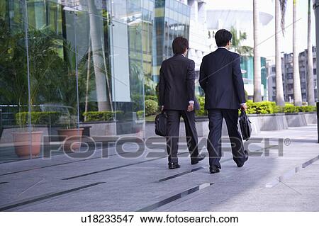 Two businessmen holding briefcase and walking together View Large Photo Image Stock Photo - Two businessmen holding briefcase and walking together. Fotosearch