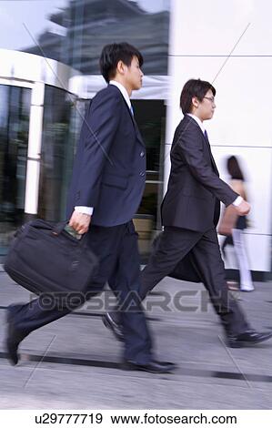 Two businessmen holding briefcase and walking together View Large Photo Image Stock Photo - Two businessmen holding briefcase and walking together. Fotosearch