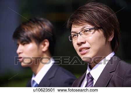 Stock Image - Two businessmen looking away together. Fotosearch