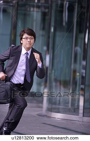 Young businessman holding briefcase and running View Large Photo Image Stock Image - Young businessman holding briefcase and running. Fotosearch