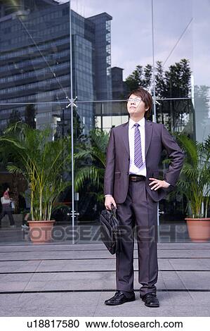 Young businessman holding briefcase and looking up View Large Photo Image Stock Image - Young businessman holding briefcase and looking up. Fotosearch