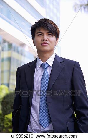 Stock Image - Young businessman looking away with anticipation. Fotosearch