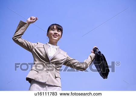 Young businesswoman holding briefcase with arms outstretched and looking away with smile View Large Photo Image Stock Image - Young businesswoman holding briefcase with arms outstretched and looking away with smile. Fotosearch