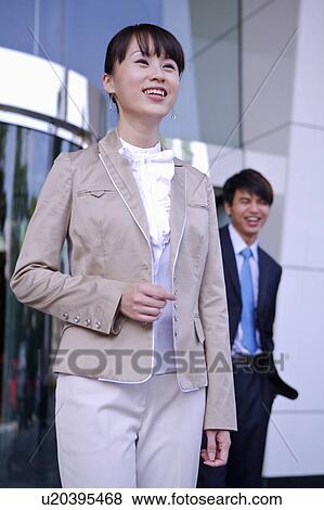 Stock Photo - Young man and woman smiling happily and looking away. Fotosearch