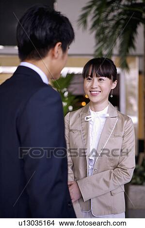 Picture - Young woman and man talking together and smiling. Fotosearch