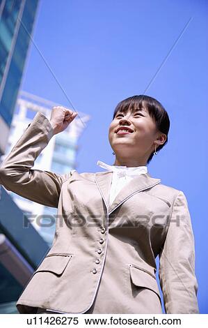 Stock Photography - Young woman looking up with fists up and smiling. Fotosearch