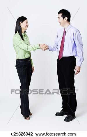 Stock Image - Businesswoman and a businessman shaking hands. Fotosearch
