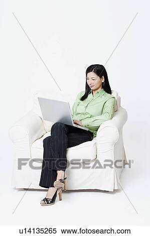 Stock Photography - Businesswoman sitting in an armchair and using a laptop. Fotosearch