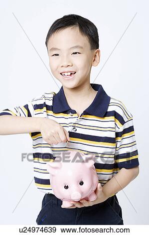 Close-up of a boy putting a coin into a piggy bank View Large Photo Image Stock Photo - Close-up of a boy putting a coin into a piggy bank. Fotosearch