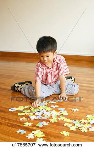 Stock Photo - Close-up of a boy sitting and playing with puzzles. Fotosearch