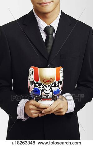 Close-up of a businessman holding a mask View Large Photo Image Stock Photo - Close-up of a businessman holding a mask. Fotosearch