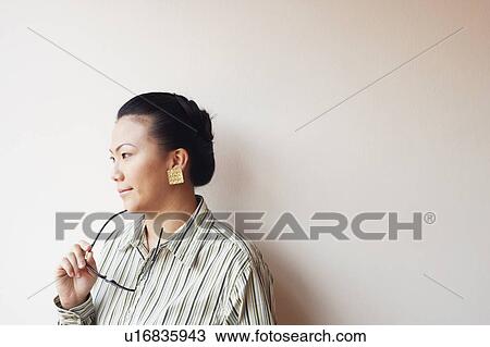 Close-up of a businesswoman holding eyeglasses and looking away View Large Photo Image Stock Image - Close-up of a businesswoman holding eyeglasses and looking away. Fotosearch