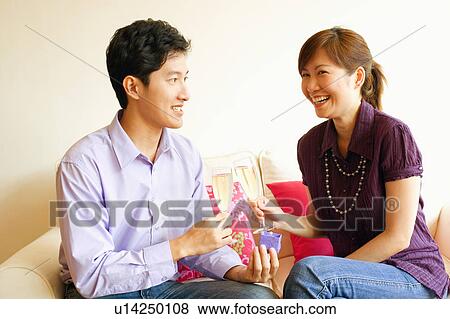Stock Photo - Close-up of a couple smiling and toasting champagne flutes. Fotosearch