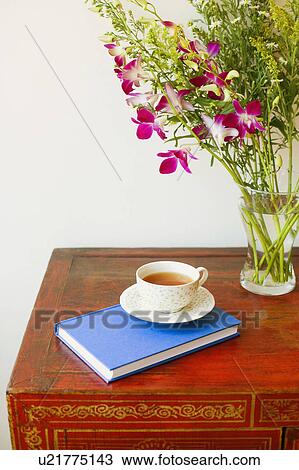 Stock Image - Close-up of a cup on a diary near a vase. Fotosearch