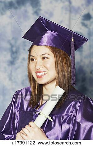 Stock Image - Close-up of a female graduate holding a diploma. Fotosearch
