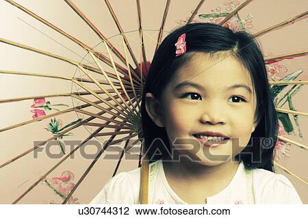 Stock Image - Close-up of a girl holding a parasol and smiling. Fotosearch