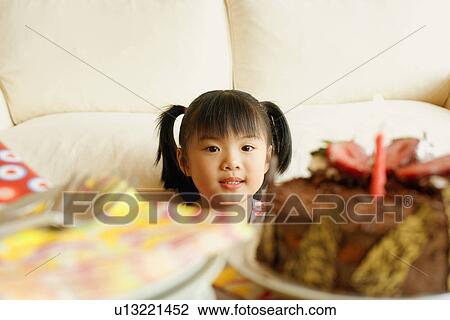 Stock Image - Close-up of a girl looking at a cake. Fotosearch