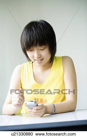 Stock Image - Close-up of a girl operating a mobile phone. Fotosearch