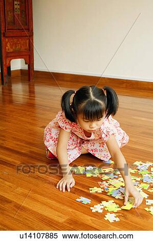 Close-up of a girl sitting on the floor and playing with a jigsaw puzzle View Large Photo Image Stock Photography - Close-up of a girl sitting on the floor and playing with a jigsaw puzzle. Fotosearch