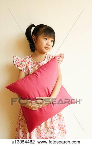 Close-up of a girl standing and holding a pillow View Large Photo Image Stock Image - Close-up of a girl standing and holding a pillow. Fotosearch