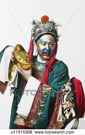 Stock Photo - Close-up of a male Chinese opera performer holding a bowl full of gold coins. Fotosearch