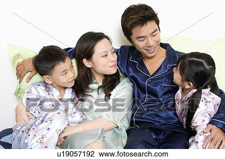Close-up of a mid adult man and a young woman with their children on the bed View Large Photo Image Stock Image - Close-up of a mid adult man and a young woman with their children on the bed. Fotosearch